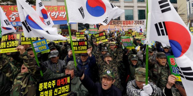 South Korean Vietnam War veterans with national flags shout slogans during a rally denouncing former Unified Progressive Party lawmaker Lee Seok-ki near the Supreme Court in Seoul, South Korea, Thursday, Jan. 22, 2015. South Koreaâs Supreme Court on Thursday upheld a prison sentence for Lee arrested for encouraging an armed rebellion in the South should war with North Korea break out. The letters on placards read