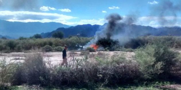A man stands near the smoking remains of a helicopter that crashed with another near Villa Castelli in the La Rioja province of Argentina, Monday, March 9, 2015. Two helicopters carrying passengers filming the popular European reality show âDroppedâ crashed Monday in a remote area of northwest Argentina, killing everyone on board, authorities said. (AP Photo/Gabriel Gonzalez)