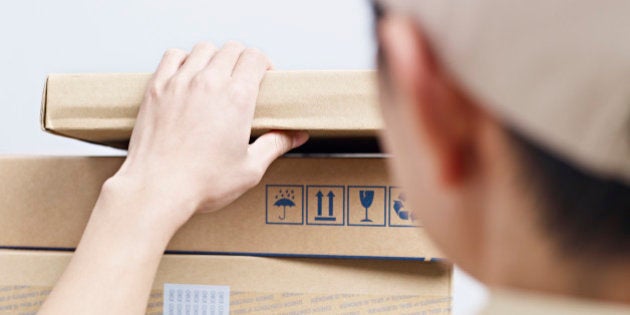 rear view of a male asian delivery man checking packages to be delivered.