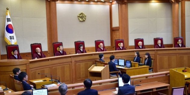 Park Han-Chul (top C), the chief judge of South Korea's Constitutional Court, delivers judgment on the government's petition to disband the Unified Progressive Party (UPP) in Seoul on December 19, 2014. South Korea's nascent far-left political party was disbanded in a rare decision by the court which stigmatised it as a pro-North Korean group. AFP PHOTO / POOL / JUNG YEON-JE (Photo credit should read JUNG YEON-JE/AFP/Getty Images)