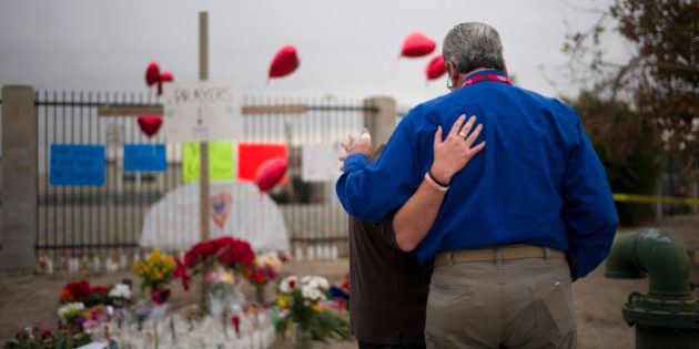 Chaplain Chuck Bender, right, prays with Michael Davila at a makeshift memorial honoring the victims of Wednesday's shooting rampage, Friday, Dec. 4, 2015, in San Bernardino, Calif. The FBI said Friday it is officially investigating the mass shooting in California as an act of terrorism, while a U.S. law enforcement official said the woman who carried out the attack with her husband had pledged allegiance to the Islamic State group and its leader on Facebook. (AP Photo/Jae C. Hong)