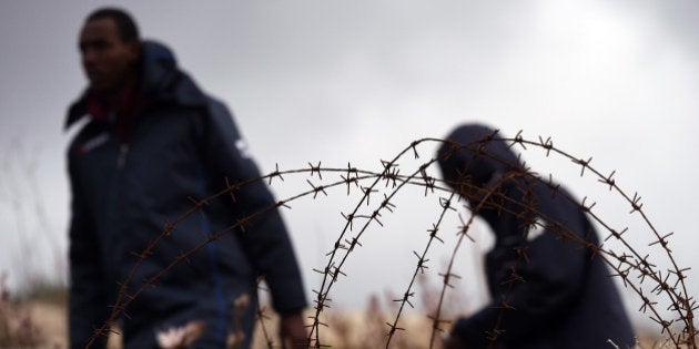 LAMPEDUSA, ITALY - FEBRUARY 19: Migrants walk past barbed wire fences at the Temporary Permanence Centre (CPT) on February 19, 2015 in Lampedusa, Italy. Hundreds of migrants have recently arrived in Lampedusa after fleeing the attacks by ISIS in Libya. The Temporary Permanence Centre (CPT) of Lampedusa, which was designed to accommodate 250 people currently holds about 1,200 migrants following Sunday's rescue of 2,000 in the Mediterranean Sea, between the island of Lampedusa and the Libyan coast. (Photo by Tullio M. Puglia/Getty Images)