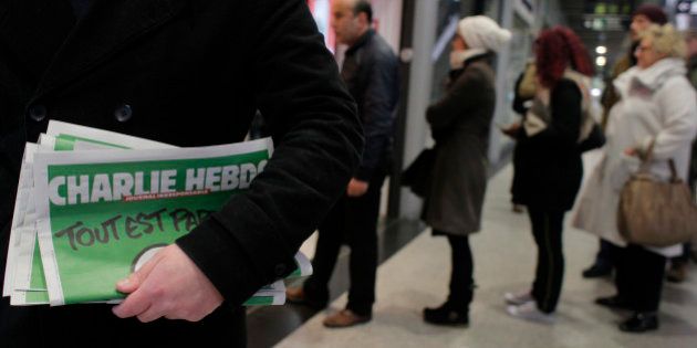 A man leaves after buying Charlie Hebdo newspapers as people queue at a newsstand in Paris, Wednesday, Jan. 14, 2015. In an emotional act of defiance, Charlie Hebdo resurrected its irreverent and often provocative newspaper, featuring a caricature of the Prophet Muhammad on the cover that drew immediate criticism and threats of more violence. (AP Photo/Christophe Ena)