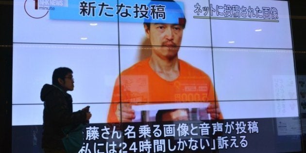 A pedestrian looks at a large screen in Tokyo on January 28, 2015 showing television news reports about Japanese hostage Kenji Goto who has been kidnapped by the Islamic State group. Japan has asked Jordan for help after the Islamic State jihadist group threatened to kill a Japanese journalist and a Jordanian pilot within 24 hours unless Amman frees a jailed female militant. AFP PHOTO / KAZUHIRO NOGI (Photo credit should read KAZUHIRO NOGI/AFP/Getty Images)