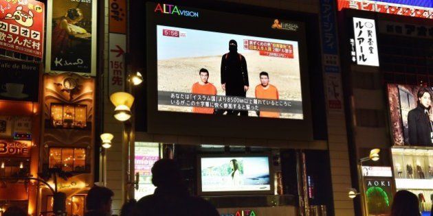 People look at a large TV screen in Tokyo on January 20, 2015 showing news reports about two Japanese men (in orange) who have been kidnapped by the Islamic State group. Japanese Prime Minister Shinzo Abe, speaking at a press conference during a visit to Jerusalem on January 20, demanded that the Islamic State group immediately free the two Japanese hostages unharmed after the jihadists posted a video threat to kill them. AFP PHOTO / Yoshikazu TSUNO (Photo credit should read YOSHIKAZU TSUNO/AFP/Getty Images)