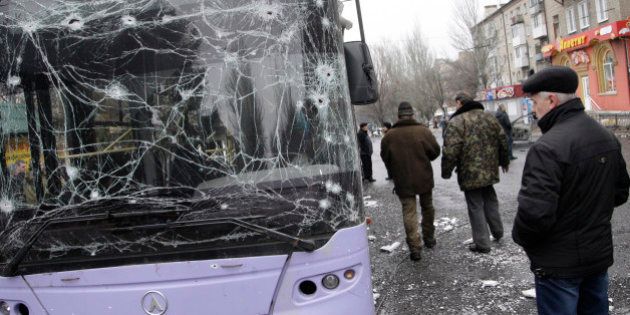 DONETSK, UKRAINE - JANUARY 22 : People gather next to a damaged bus after a mortar shell hit near bus station in Donetsk on January 22, 2015. At least 13 people died and many injured after a mortar shell hits near a bus stop in downtown of Donetsk, Ukraine on January 22, 2015. (Photo by Alexander Ermochenko/Anadolu Agency/Getty Images)