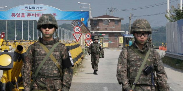 A South Korean amy soldier walks as his colleague soldiers stand guard on Unification Bridge, which leads to the demilitarized zone, near the border village of Panmunjom in Paju, South Korea, Sunday, Aug. 23, 2015. The first high-level talks in nearly a year between South Korea and North Korea were adjourned after stretching into the early hours of Sunday, as the rivals looked to defuse mounting tensions that have pushed them to the brink of a possible military confrontation. (AP Photo/Ahn Young-joon)