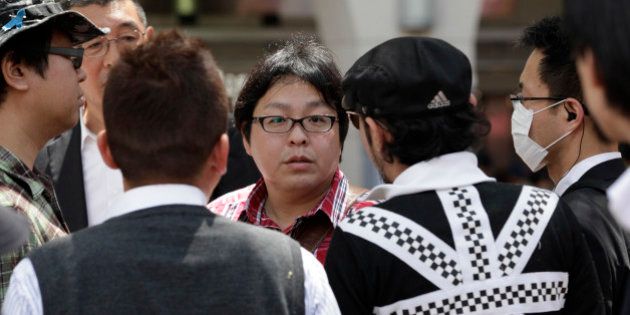 In this photo taken Sunday, May 12, 2013, Makoto Sakurai, center, leader of anti-Korean activist group Zaitokukai, is confronted by a man, second right wearing a cap, who protests against the group's hate speech street rally in Tokyo. Anti-Korean rallies have escalated this year and spread to other cities with Korean communities. In Tokyo's Shin-Okubo district, dotted with Korean restaurants and shops popular among South Korean pop-culture fans, hundreds of Zaitokukai members and supporters have called Koreans