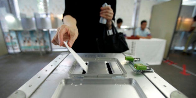 A voter casts her ballot for the Japanese parliament's upper house election at a polling station in Tokyo, Japan, on Sunday, July 21, 2013. Japanese voters are set to hand Prime Minister Shinzo Abe control of both houses of Parliament, giving him a mandate to extend his overhaul of the world's third-biggest economy. Photographer: Kiyoshi Ota/Bloomberg via Getty Images