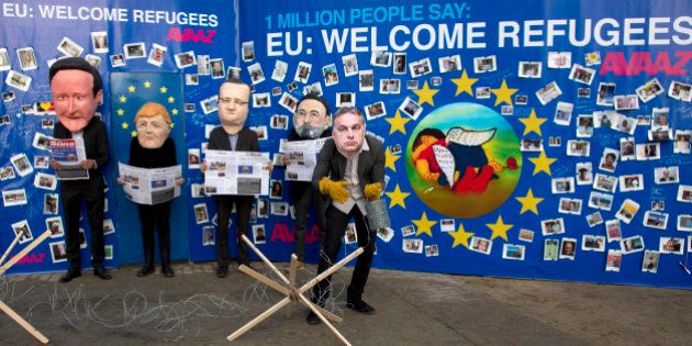 Actors dressed with face masks of EU leaders, from left, British Prime Minister David Cameron, German Chancellor Angela Merkel, French President Francois Hollande, Spanish Prime Minister Mariano Rajoy and Hungarian Prime Minister Viktor Orban pose in front of a painting of the late Aylan Kurdi on a refugee message board outside of EU headquarters in Brussels on Monday, Sept. 14, 2015. Aylan Kurdi, 3, was found dead on a Turkish beach after the small rubber boat he and his family were in capsized in a desperate voyage from Turkey to Greece. EU interior ministers meet on Monday to discuss the migration crisis. (AP Photo/Virginia Mayo)