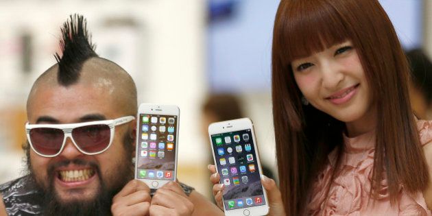 A customer and actress Sayaka Kanda pose for photographers during a ceremony to mark the first day of sales of the latest iPhone 6 and 6 Plus at a store in Tokyo Friday, Sept. 19, 2014. (AP Photo/Shizuo Kambayashi)