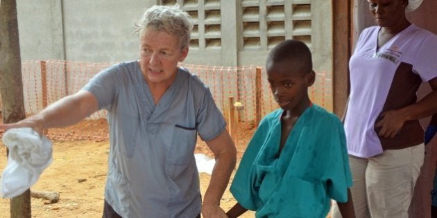 A 10-year-old boy walks with a doctor from Christian charity Samaritan's Purse, after being taken out of quarantine and receiving treatment following his mother's death caused by the ebola virus, in the group's Ebola treatment center, at the ELWA hospital in the Liberian capital Monrovia, on July 24, 2014. A US doctor battling West Africa's Ebola epidemic has himself fallen sick with the disease in Liberia, Samaritan's Purse said on July 27. AFP PHOTO / ZOOM DOSSO (Photo credit should read ZOOM DOSSO/AFP/Getty Images)