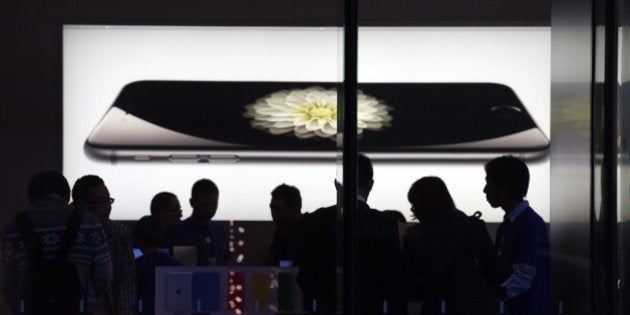 Store attendants help customers at an Apple store selling the iPhone 6 in Beijing on October 23, 2014. During a trip to Shanghai last January, Apple CEO Tim Cook said he expects China to surpass the United States to become Apple's largest market. AFP PHOTO/Greg BAKER (Photo credit should read GREG BAKER/AFP/Getty Images)