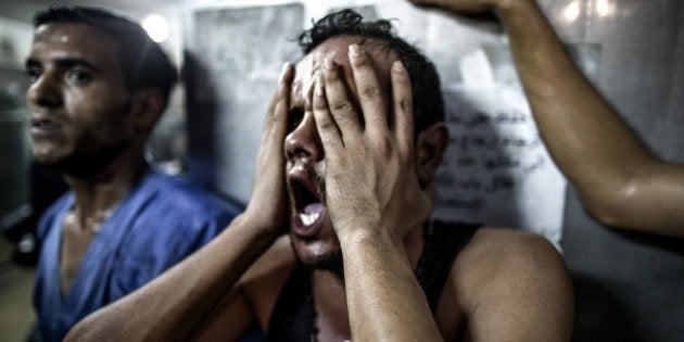 A relative reacts after seeing the bodies of three Palestinian children, killed in an explosion in a public playground on the beachfront of Shati refugee camp, as they lie in the morgue of al-Shifa hospital in Gaza City on July 28, 2014. Palestinian medical sources blamed death of eight Palestinian children on air strikes launched by the Israeli military, which in turn said Hamas had misfired its own rockets at the camp and at the Shifa hospital. AFP PHOTO/MARCO LONGARI (Photo credit should read MARCO LONGARI/AFP/Getty Images)