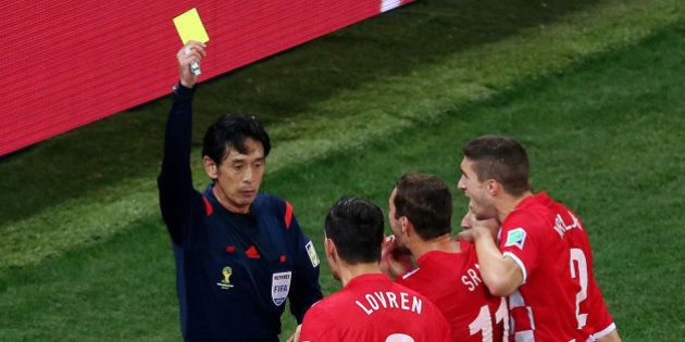 SAO PAULO, BRAZIL - JUNE 12: Referee Yuichi Nishimura shows Dejan Lovren of Croatia (2nd L) a yellow card and awards a penalty kick during the 2014 FIFA World Cup Brazil Group A match between Brazil and Croatia at Arena de Sao Paulo on June 12, 2014 in Sao Paulo, Brazil. (Photo by Elsa/Getty Images)