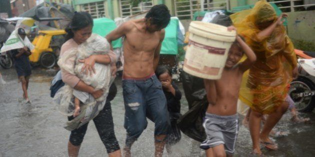 Residents brave strong winds and rain as they evacuate from their homes at an informal settlers' area as Typhoon Rammasun barrels across Manila on July 16, 2014. Typhoon Rammasun shut down the Philippine capital on July 16 as authorities said the first major storm of the country's brutal rainy season claimed at least one life and forced hundreds of thousands to evacuate. AFP PHOTO/TED ALJIBE (Photo credit should read TED ALJIBE/AFP/Getty Images)