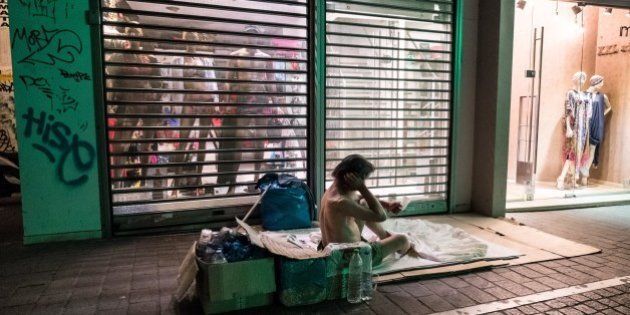 A homeless man sits on the sidewalk in front of a shop in downtown Athens on July 6 2015. Greeks declared in a referendum that they 'deserve better' and 'cannot accept a non-viable solution' to the country's debt crisis, new Finance Minister Euclid Tsakalotos said upon taking office on Monday. AFP PHOTO / ANDREAS SOLARO (Photo credit should read ANDREAS SOLARO/AFP/Getty Images)