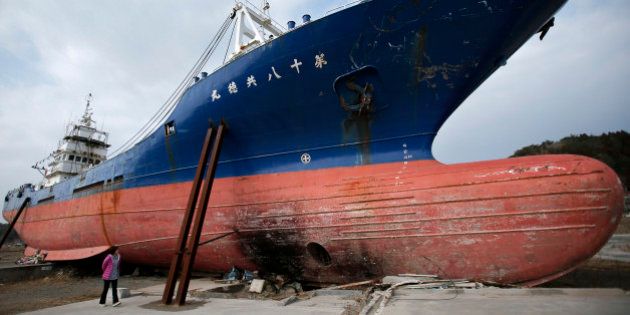 A woman looks at a vessel swept inland by the tsunami following the Great East Japan Earthquake in Kesennuma, Miyagi Prefecture, Japan, on Sunday, March 10, 2013. Japan's economy grew at an annualized 0.2 percent last quarter after shrinking 3.7 percent the three previous months, the worst since the 2011 earthquake, revised government data show. Photographer: Kiyoshi Ota/Bloomberg via Getty Images