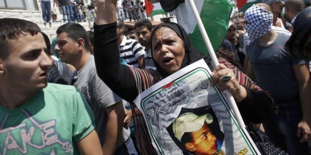 Mourners rally for the funeral of Palestinian youth Mohammed Abu Khder, 16, as they carry his body to the mosque during his funerals in Shuafat, in Israeli annexed East Jerusalem, on July 4, 2014. Abu Khder, a Palestinian teenager was reportedly kidnapped and killed, triggering violent clashes in east Jerusalem, in an apparent act of revenge for the murder by militants of three Israeli youths. AFP PHOTO / THOMAS COEX (Photo credit should read THOMAS COEX/AFP/Getty Images)