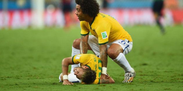 FORTALEZA, BRAZIL - JULY 04: Neymar of Brazil lies on the field after a challenge as teammate Marcelo reacts during the 2014 FIFA World Cup Brazil Quarter Final match between Brazil and Colombia at Castelao on July 4, 2014 in Fortaleza, Brazil. (Photo by Jamie McDonald/Getty Images)