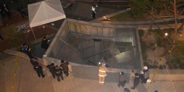 SEONGNAM, SOUTH KOREA - OCTOBER 17: (SOUTH KOREA OUT) In this handout picture provided by the Park Young-Dae-Donga Daily, Rescue workers stand around a collapsed ventilation grate on October 17, 2014 in Seongnam, South Korea. People on ventilation grate fell 20 metres when the grate collapsed while watching an outdoor concert of popular K-pop group 4Minute. (Photo by Park Young-Dae-Donga Daily via Getty Images).