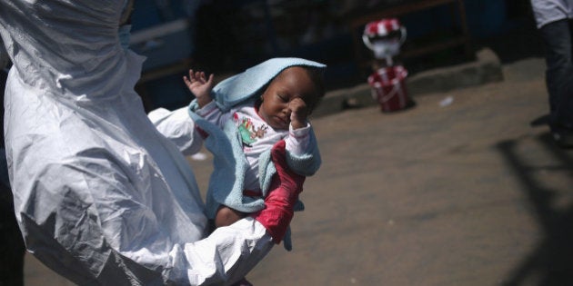 MONROVIA, LIBERIA - OCTOBER 17: A health worker carries Benson, 2 months, to a re-opened Ebola holding center in the West Point neighborhood on October 17, 2014 in Monrovia, Liberia. The baby, her mother and grandmother were all taken to the center after an Ebola tracing coordinator checked their temperature and found they all had fever. A family member living in the home had died only the day before from Ebola. The West Point holding center was re-opened this week with community support, two months after a mob overran the facility and looted it's contents, many denying the presence of Ebola in their community. The World Health Organization says that more than 4,500 people have died due to the Ebola epidemic in West Africa with a 70 percent mortality rate for those infected with the virus. (Photo by John Moore/Getty Images)