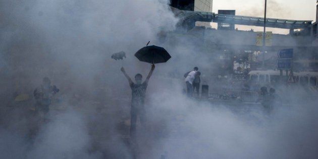 TOPSHOTSA pro-democracy demonstrator gestures after police fired tear gas towards protesters near the Hong Kong government headquarters on September 28, 2014. Police fired tear gas as tens of thousands of pro-democracy demonstrators brought parts of central Hong Kong to a standstill on September 28, in a dramatic escalation of protests that have gripped the semi-autonomous Chinese city for days. AFP PHOTO / XAUME OLLEROS (Photo credit should read XAUME OLLEROS/AFP/Getty Images)