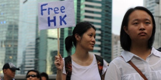 A protester displays a placard during a pro-democracy rally seeking greater democracy in Hong Kong on July 1, 2014 as frustration grows over the influence of Beijing on the city. July 1 is traditionally a day of protest in Hong Kong and also marks the anniversary of the handover from Britain to China in 1997, under a 'one country, two systems' agreement. AFP PHOTO / DALE DE LA REY (Photo credit should read DALE de la REY/AFP/Getty Images)