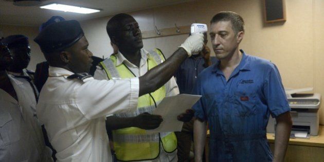Health officials takes the body temperature of an Ukrainian sailor on the MV Pintail ship, as they check for signs of the Ebola virus at the Apapa Sea Port, in Lagos, on September 29, 2014. Health officials have begun the screening of cargo ship crews transiting through the ports of Nigeria to prevent cross border transmission of Ebola through sea and cargo ports. Nigeria has cleared all patients under surveillance for the Ebola virus, the federal health ministry said on September 24, 2014. 'There is nobody again under surveillance for the Ebola virus in any part of Nigeria. All those under surveillance have completed their mandatory 21-day period stipulated by the WHO,' ministry's spokesman Dan Nwomeh told AFP, referring to the World Health Organization. PHOTO/PIUS UTOMI EKPEI (Photo credit should read PIUS UTOMI EKPEI/AFP/Getty Images)