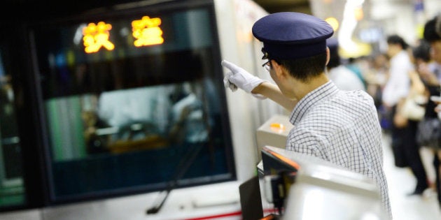 TO GO WITH Japan-transport-leisure-tourism-subway,FEATURE by Hiroshi HIYAMAThis photo taken on July 12, 2013 shows a station attendant pointing to check the destination of a subway train on the Marunouchi Line at Ikebukuro Station in Tokyo. The vast train network that criss-crosses subterranean Tokyo can be a confusing and intimidating place for the uninitiated. The city actually has two public subway operators: Tokyo Metro and Toei Subway, and between them they carry nearly 10 million passengers daily. AFP PHOTO / Toru YAMANAKA (Photo credit should read TORU YAMANAKA/AFP/Getty Images)