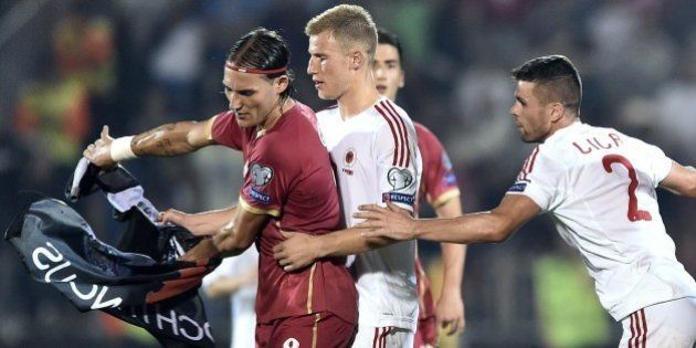 Serbia's Nemanja Gudelj (L) scuffles with midfielder Albania's midfielder Bekim Balaj (C) and defender Andi Lila (R) over a flag with Albanian national symbols pulled down from a remotely operated drone flown over the pitch during the EURO 2016 group I football match between Serbia and Albania in Belgrade on October 14, 2014. AFP PHOTO / ANDREJ ISAKOVIC (Photo credit should read ANDREJ ISAKOVIC/AFP/Getty Images)
