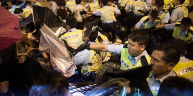 Police and pro-democracy protesters scuffle during a confrontation outside the central government offices in the Admiralty district of Hong Kong on October 15, 2014. Hong Kong police vowed October 14 to tear down more street barricades manned by pro-democracy protesters, hours after hundreds of officers armed with chainsaws and boltcutters partially cleared two major roads occupied for a fortnight. AFP PHOTO / Ed Jones (Photo credit should read ED JONES/AFP/Getty Images)