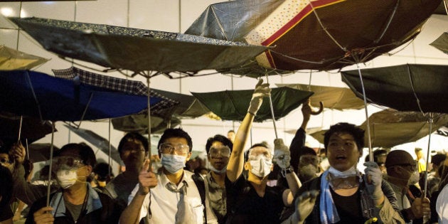 HONG KONG - OCTOBER 14: Pro-democracy protesters use umbrellas to protect themselves from police's pepper spray on a street outside of Hong Kong Government Complex on October 14, 2014 in Hong Kong. Pro-democracy protesters took over Lung Wo Road after police cleared off the barricades on Queen's Road. Protesters continue to call for open elections and the resignation of Hong Kong's Chief Executive Leung Chun-ying. (Photo by Anthony Kwan/Getty Images)