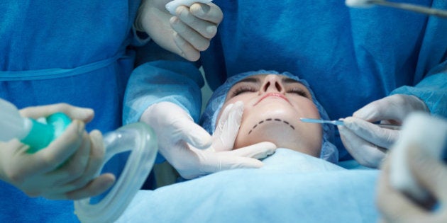 Young woman lying on operating table during facial plastic surgery