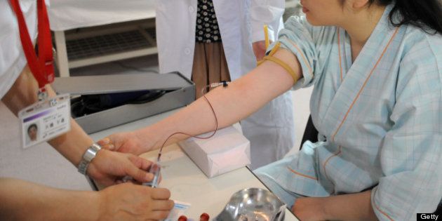 TO GO WITH Japan-China-tourism-medicine-health,FEATURE by Kyoko Hasegawa This photo taken on July 13, 2012 shows Chinese tourist Zhang Lan (R) has blood taken during a check-up at a hospital in Asahikawa, Hokkaido prefecture. Treatments there range from head-to-toe checkups, with a focus on cancer screening and neurological diseases, to anti-ageing and cosmetic surgery, including breast enhancements and liposuction. AFP PHOTO / TOSHIFUMI KITAMURA (Photo credit should read TOSHIFUMI KITAMURA/AFP/Getty Images)