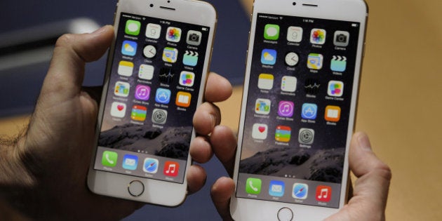 An attendee displays the new Apple Inc. iPhone 6, left, and iPhone 6 Plus for a photograph after a product announcement at Flint Center in Cupertino, California, U.S., on Tuesday, Sept. 9, 2014. Apple Inc. unveiled redesigned iPhones with bigger screens, overhauling its top-selling product in an event that gives the clearest sign yet of the company's product direction under Chief Executive Officer Tim Cook. Photographer: David Paul Morris/Bloomberg via Getty Images