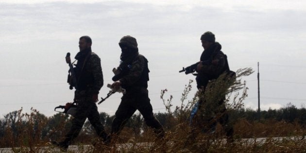 Ukrainian soldiers walk at a checkpoint controlled by Ukrainian forces on September 10, 2014, near the small eastern Ukrainian city of Slavyanoserbsk, in the Lugansk region. German Chancellor Angela Merkel called on September 10 for the European Union to move quickly on new sanctions against Russia, saying they could always be lifted if a Ukraine ceasefire holds. Ukrainian President Petro Poroshenko said on September 10 that Russia had withdrawn most of the troops it allegedly snuck across the border to bolster pro-Kremlin rebels, and vowed greater autonomy for the separatist east in order to sustain a fragile new truce. AFP PHOTO/ ANATOLII STEPANOV (Photo credit should read ANATOLII STEPANOV/AFP/Getty Images)