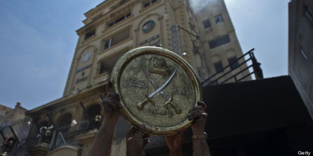 Egyptians hold a plaque of the Muslim Brotherhood emblem which was removed from the party's burnt headquarters in the Moqattam district of Cairo on July 1, 2013 after it was set ablaze by opposition demonstrators overnight. Egypt's opposition gave Islamist Mohamed Morsi a day to quit or face civil disobedience after deadly protests demanded the country's first democratically elected president step down after just a year in office. AFP PHOTO / KHALED DESOUKI (Photo credit should read KHALED DESOUKI/AFP/Getty Images)