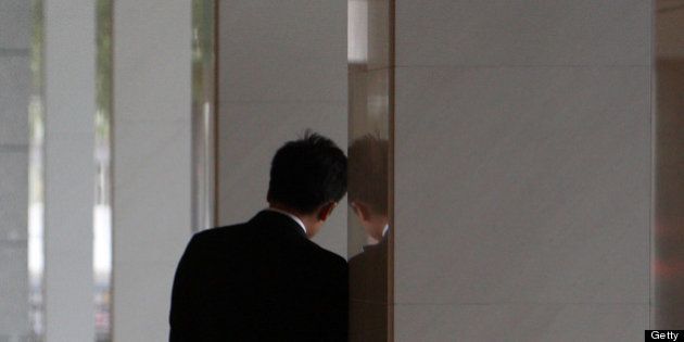 A businessman leans on the entrance to a building in Tokyo, Japan, on Tuesday, Nov. 30, 2010. Japan's industrial production decreased and the unemployment rate unexpectedly climbed in October, providing early signs that the country's economy will likely shrink this quarter. Photographer: Tomohiro Ohsumi/Bloomberg via Getty Images