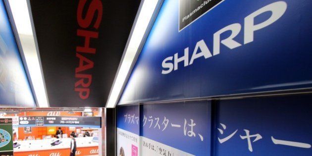 Customers walk past advertisements for Japanese electronics manufacturer Sharp at an electrics shop in...
