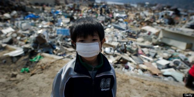 A boy stands among destroyed houses and debris in the tsunami-damaged town of Yamada, in Iwate prefecture, on March 25, 2011. Two weeks after a giant quake struck and sent a massive tsunami crashing into the Pacific coast, the death toll from Japan's worst post-war disaster topped 10,000 and there was scant hope for 17,500 others still missing. AFP PHOTO/ Nicolas ASFOURI (Photo credit should read NICOLAS ASFOURI/AFP/Getty Images)