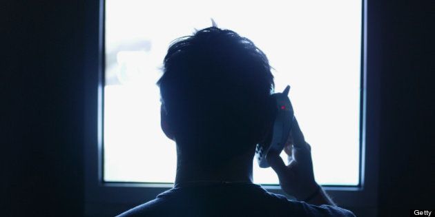 Man sitting in front of TV, talking on phone, rear view(silhouette)