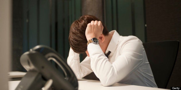 Man, young executive sitting in deep thoughts, stressed up and working late in the office environment.