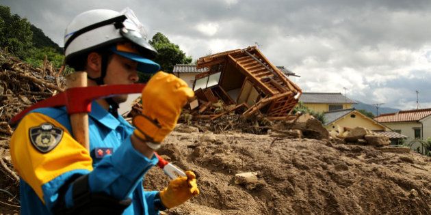 HIROSHIMA, JAPAN - AUGUST 21: Rescue teams continue the search for missing people among the debris of houses destroyed by a landslide caused by torrential rain at the site of a landslide in a residential area on August 21, 2014 in Hiroshima, Japan. Rescue work continues as at least 39 people were confirmed dead and 7 people are missing one day after the torrential rain caused flooding and landslides in the city of Hiroshima early Wednesday August 20, 2014. (Photo by Buddhika Weerasinghe/Getty Images)