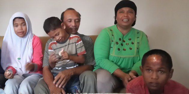 Septi Rangkuti (2nd L) holds his son Jumadi Rangkuti next to his wife Jamaliah (top R) and daugther Raudhatul Jannah (L) after being reunited with his missing son Arif Pratama Rangkuti (lower R) in Payakumbuh town on Sumatra island on August 19, 2014. The Indonesian boy was swept away by the devastating 2004 tsunami and has been reunited with his family a decade after he was given up for dead. His sister Raudhatul Jannah was also reunited with her family on August 7, 2014. Arif and her sister Raudhatul Jannah were carried off when huge waves struck their home in West Aceh district on December 26, 2004. AFP PHOTO (Photo credit should read AFP/AFP/Getty Images)
