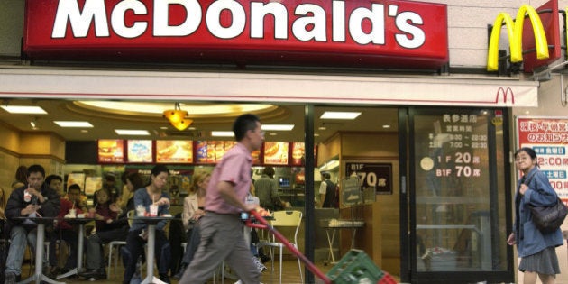 JAPAN - NOVEMBER 24: A delivery man wheels crates of bottles past a McDonald's restaurant in Tokyo on Wednesday, November 24, 2004. Japan's services industry unexpectedly expanded for a third month in four in September led by telecommunications, hotel accommodation and dining. (Photo by Michael Caronna/Bloomberg via Getty Images)