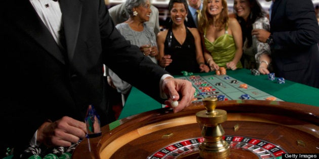 Excited friends gambling at roulette table in casino