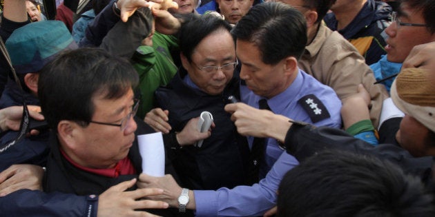 JINDO-GUN, SOUTH KOREA - APRIL 20: South Korean Ocean and Fisheries Minister Lee Ju-Young is surrounded by relatives of missing passengers of a sunken ferry as he visit a Jindo port on April 20, 2014 in Jindo-gun, South Korea. At least fifty eight people are reported dead, with 244 still missing. The ferry identified as the Sewol was carrying about 470 passengers, including the students and teachers, traveling to Jeju Island. (Photo by Chung Sung-Jun/Getty Images)