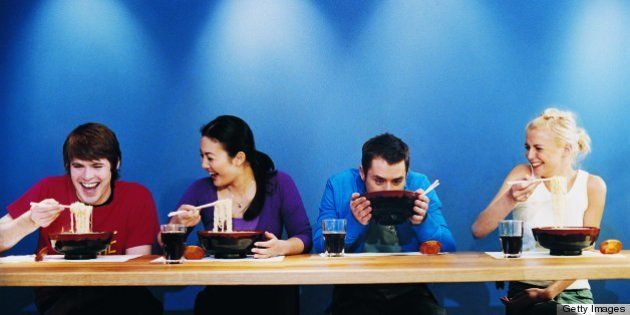 Four Young People Eating Noodles From Bowls at a Table in a Japanese Restaurant