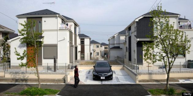 A man walks past residential properties in Yokohama, Kanagawa Prefecture, Japan, on Wednesday, April 10, 2013. Nationwide land prices on average fell 1.8 percent as of Jan. 1, compared with a 2.6 percent decline a year earlier, the Ministry of Land, Infrastructure, Transport and Tourism said in a report on March 21. Photographer: Akio Kon/Bloomberg via Getty Images